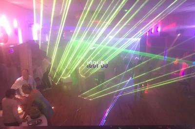 Salle de réception décorée avec des tables rondes dressées, éclairage tamisé et guirlandes lumineuses suspendues.