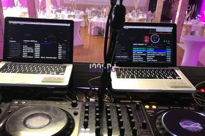 Salle de réception décorée avec des tables rondes dressées, éclairage tamisé et guirlandes lumineuses suspendues.