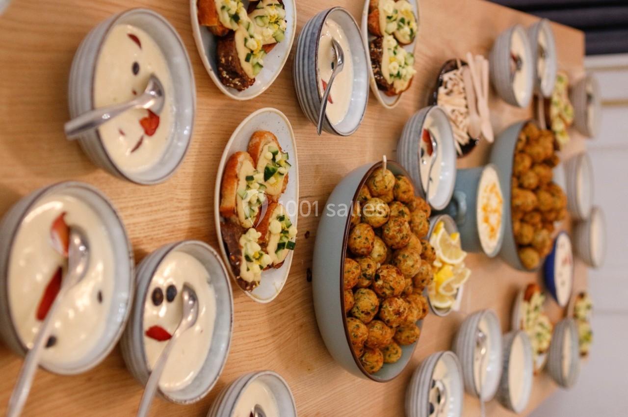 Table garnie de plats variés : boulettes, tartines garnies, sauces et accompagnements dans des assiettes et bols.