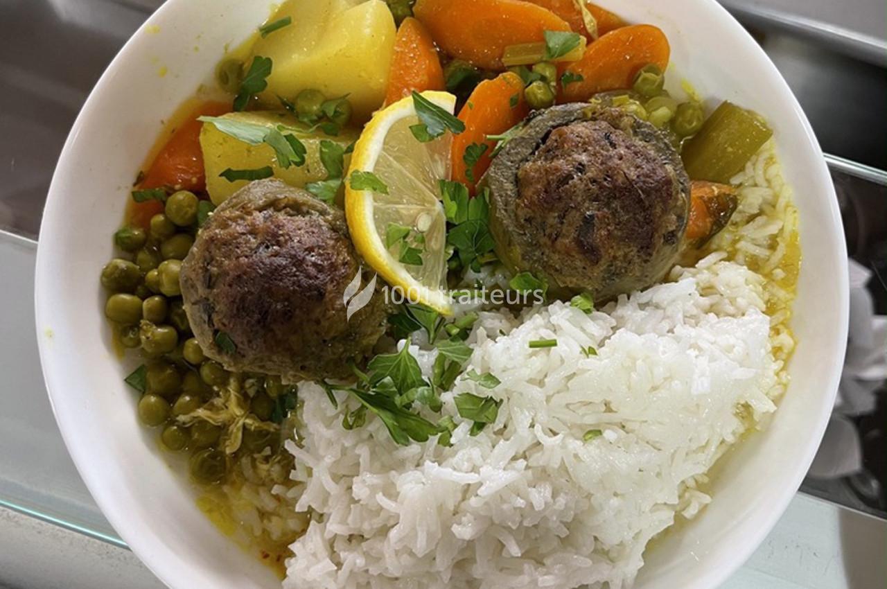 Assiette de riz blanc accompagnée de boulettes de viande, légumes mijotés, pois verts et tranche de citron.