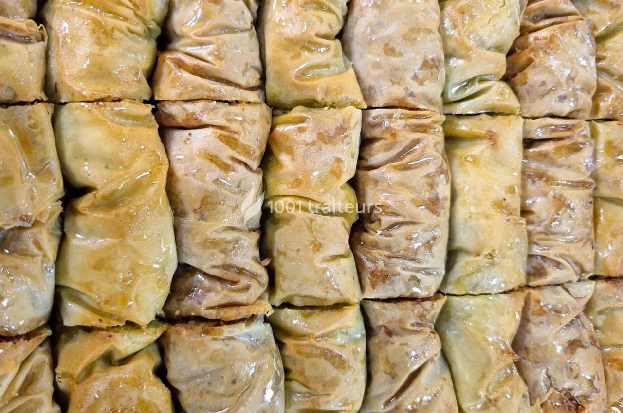 Alignement serré de pâtisseries dorées et brillantes, probablement des baklavas, avec une texture croustillante.