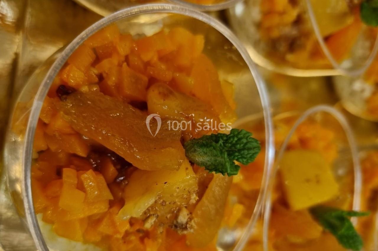 Verrines garnies de dés de fruits jaunes et oranges, décorées de feuilles de menthe fraîche.