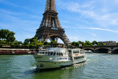 Miniature Location salle Paris 16 (Paris) - Bateau Le Rêve sur Seine #5 Un capitaine en uniforme utilise une radio dans la cabine d'un bateau, avec vue sur une rivière bordée d'arbres.
