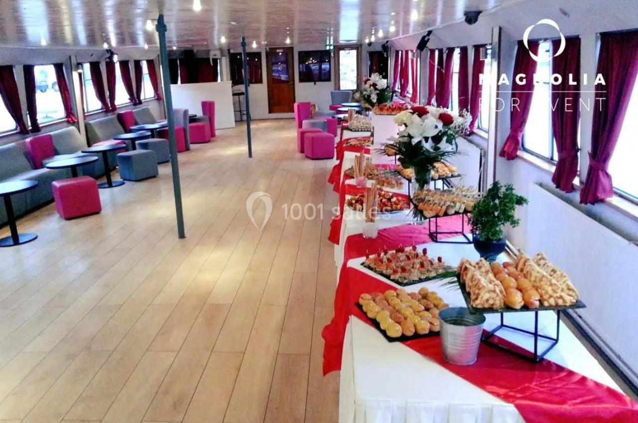 Salle de réception sur un bateau avec tables de buffet garnies de plats variés et décoration élégante.
