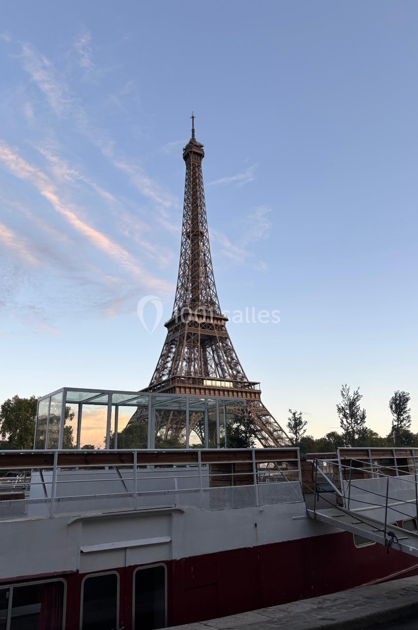 Vue de la tour Eiffel au crépuscule avec un bateau amarré au premier plan.