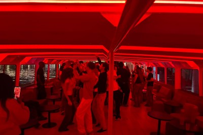 Salle intérieure d'un bateau aménagée avec des tables, des fauteuils et des ballons suspendus au plafond.