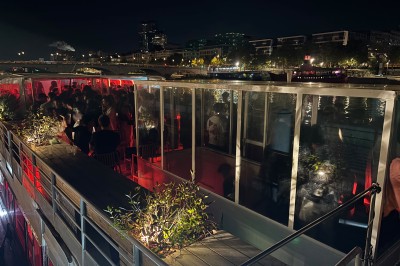 Salle intérieure d'un bateau aménagée avec des tables, des fauteuils et des ballons suspendus au plafond.
