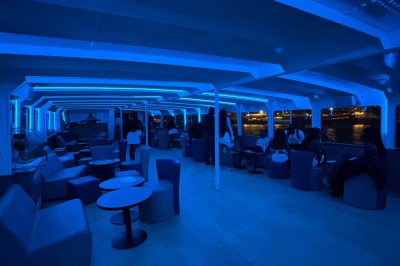 Salle intérieure d'un bateau aménagée avec des tables, des fauteuils et des ballons suspendus au plafond.