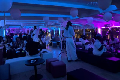 Salle intérieure d'un bateau aménagée avec des tables, des fauteuils et des ballons suspendus au plafond.