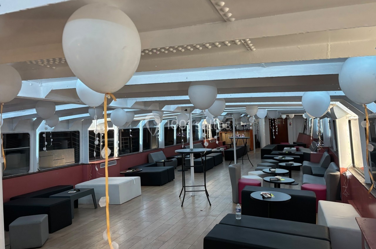 Salle décorée avec des ballons blancs, aménagée avec des tables basses et des sièges modernes dans un espace lumineux.