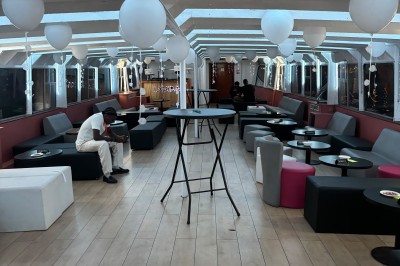 Salle intérieure d'un bateau aménagée avec des tables, des fauteuils et des ballons suspendus au plafond.
