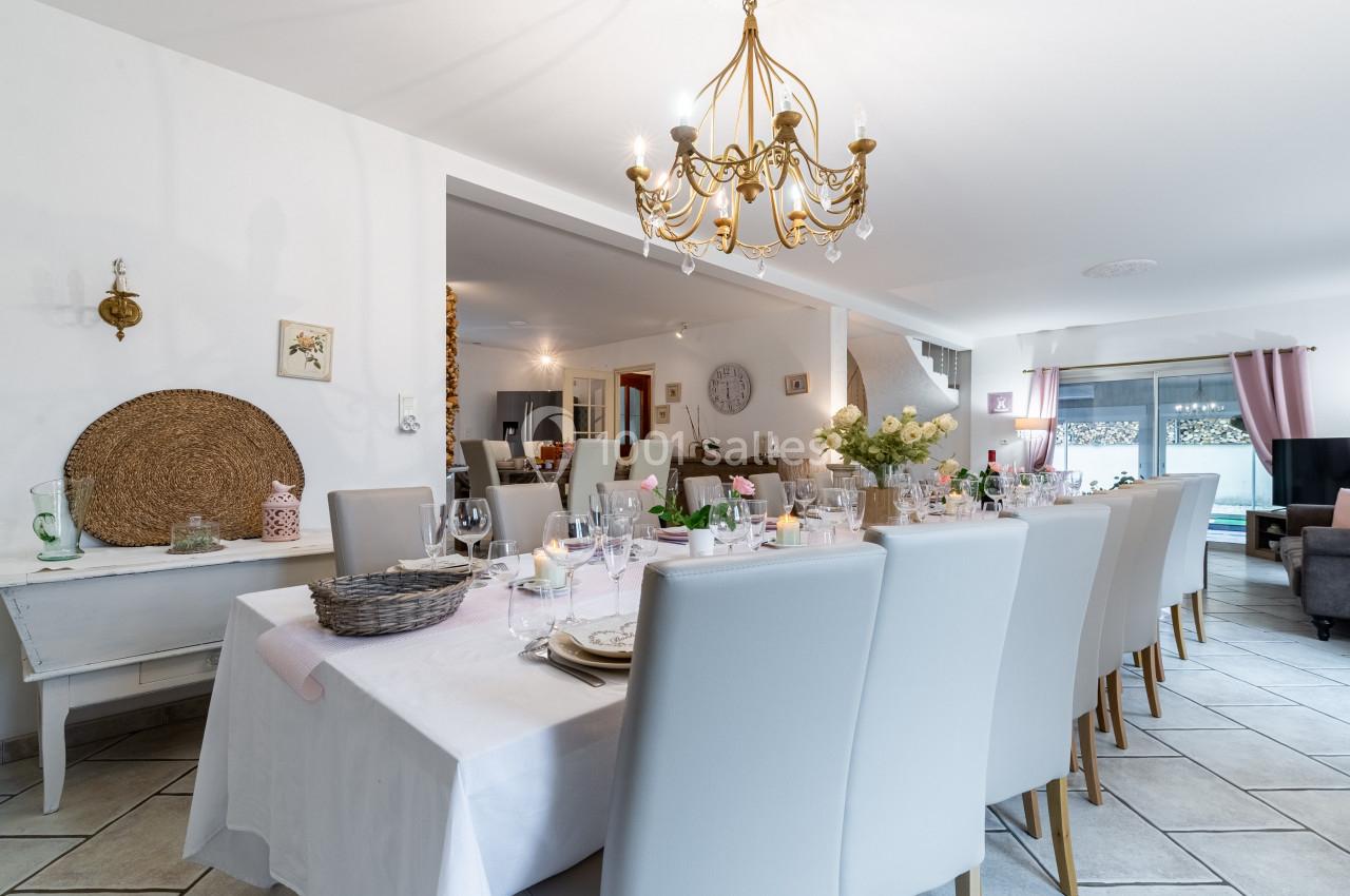 Grande table dressée avec vaisselle et décoration florale dans une salle à manger lumineuse au style moderne et chaleureux.