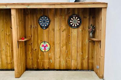 Abri en bois avec trois cibles de fléchettes fixées, une étagère avec une pomme et une autre avec un vase de fleurs.