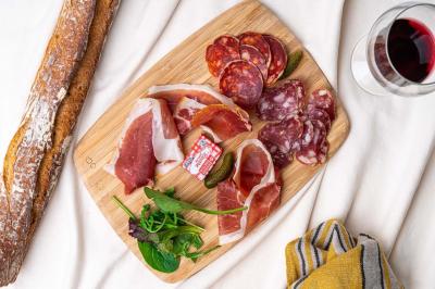 Terrasse extérieure d'un café avec tables et chaises vertes, entourée de plantes, sous un ciel ensoleillé.