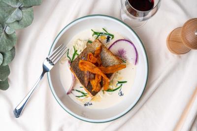 Terrasse extérieure d'un café avec tables et chaises vertes, entourée de plantes, sous un ciel ensoleillé.