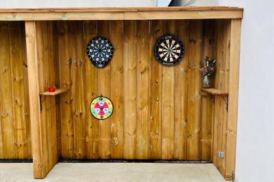 Terrasse extérieure d'un café avec tables et chaises vertes, entourée de plantes, sous un ciel ensoleillé.