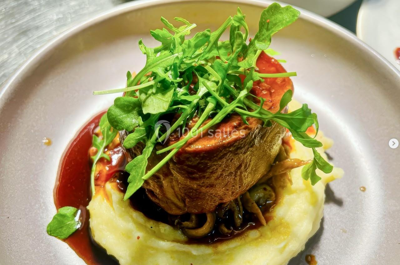 Plat composé d'une pièce de viande sur purée, nappée de sauce et garnie de roquette fraîche.