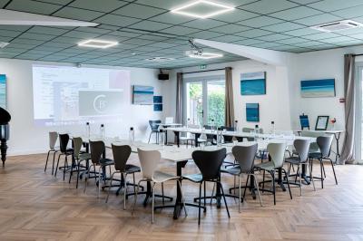 Terrasse extérieure d'un café avec tables et chaises vertes, entourée de plantes, sous un ciel ensoleillé.