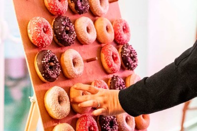 Une mariée en robe blanche pose sur une plateforme tournante lors d'un événement en extérieur, entourée d'invités.