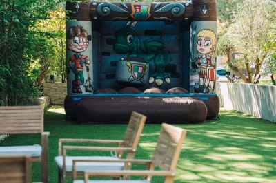 Une mariée en robe blanche pose sur une plateforme tournante lors d'un événement en extérieur, entourée d'invités.