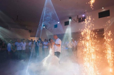 Une mariée en robe blanche pose sur une plateforme tournante lors d'un événement en extérieur, entourée d'invités.