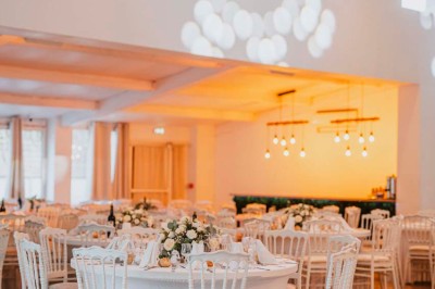 Une mariée en robe blanche pose sur une plateforme tournante lors d'un événement en extérieur, entourée d'invités.