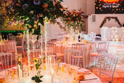 Une mariée en robe blanche pose sur une plateforme tournante lors d'un événement en extérieur, entourée d'invités.