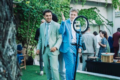 Une mariée en robe blanche pose sur une plateforme tournante lors d'un événement en extérieur, entourée d'invités.