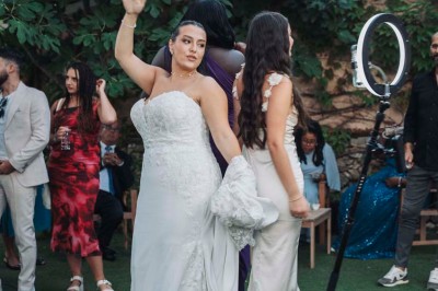 Une mariée en robe blanche pose sur une plateforme tournante lors d'un événement en extérieur, entourée d'invités.