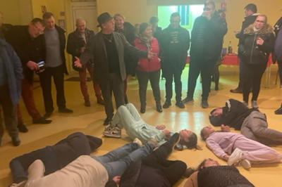 Un hypnotiseur anime une séance devant un public assis dans une salle, dans le cadre d'une cérémonie officielle.