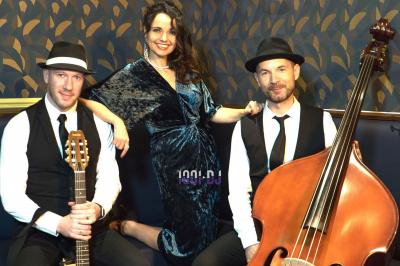 Groupe de musiciens jouant sur scène dans une salle élégante avec un grand lustre et un public dansant.