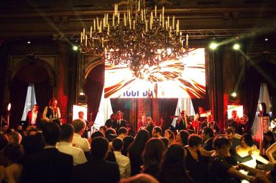 Groupe de musiciens jouant sur scène dans une salle élégante avec un grand lustre et un public dansant.