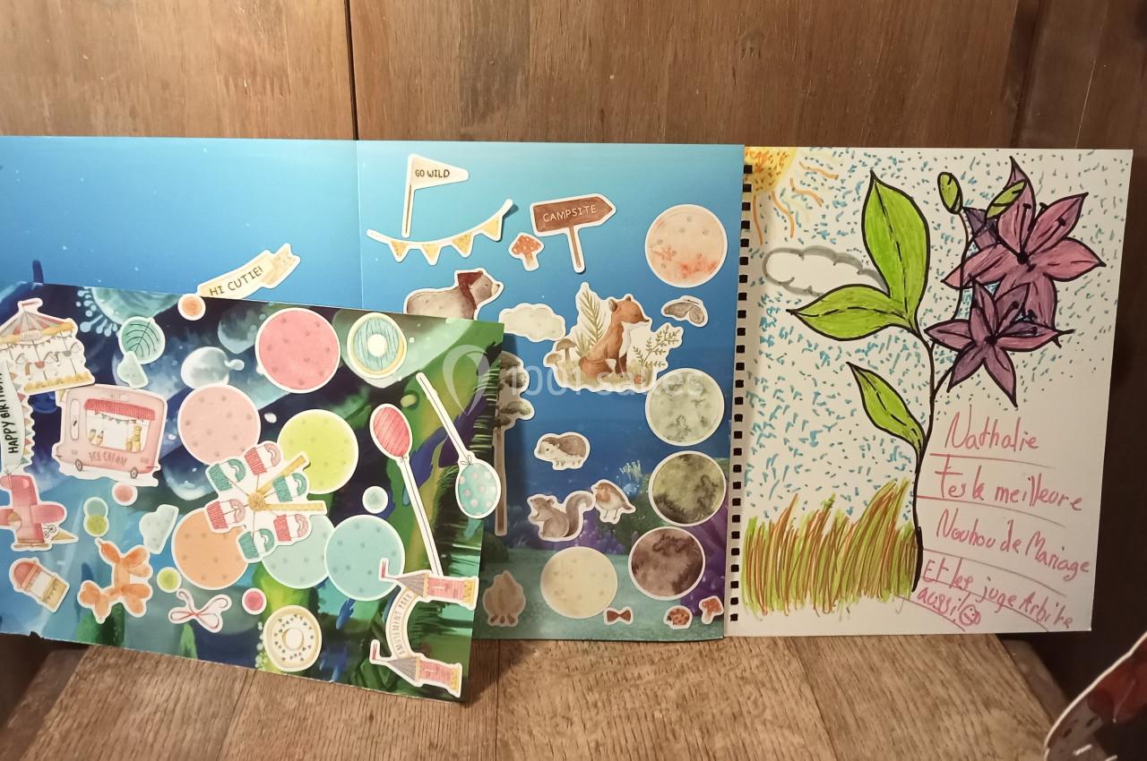 Carnets décorés avec des autocollants colorés et un dessin de fleur violette, posés sur une surface en bois.