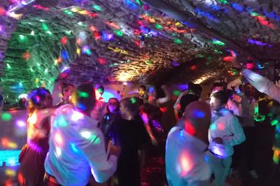 Salle de réception avec tables dressées, vue depuis une scène équipée d'une console de mixage lumineuse.