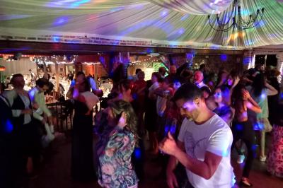 Salle de réception avec tables dressées, vue depuis une scène équipée d'une console de mixage lumineuse.