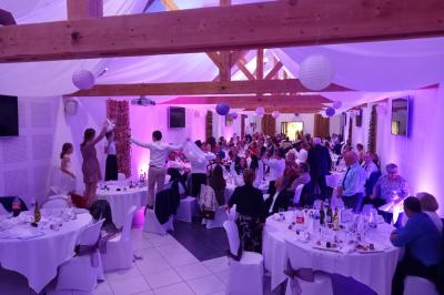 Salle de réception avec tables dressées, vue depuis une scène équipée d'une console de mixage lumineuse.