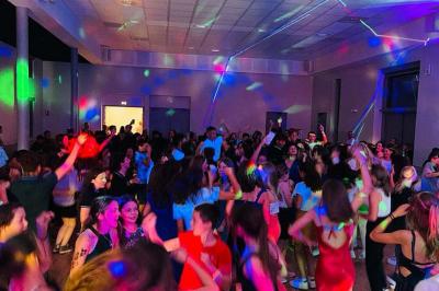 Salle de réception avec tables dressées, vue depuis une scène équipée d'une console de mixage lumineuse.