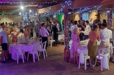 Salle de réception avec tables dressées, vue depuis une scène équipée d'une console de mixage lumineuse.