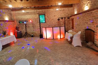 Salle de réception avec tables dressées, vue depuis une scène équipée d'une console de mixage lumineuse.