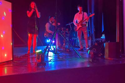 Salle de réception avec tables dressées, vue depuis une scène équipée d'une console de mixage lumineuse.