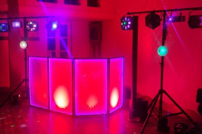 Salle de réception avec tables dressées, vue depuis une scène équipée d'une console de mixage lumineuse.