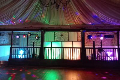 Salle de réception avec tables dressées, vue depuis une scène équipée d'une console de mixage lumineuse.