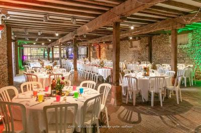 Salle de réception avec tables dressées, vue depuis une scène équipée d'une console de mixage lumineuse.