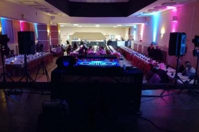 Salle de réception avec tables dressées, vue depuis une scène équipée d'une console de mixage lumineuse.