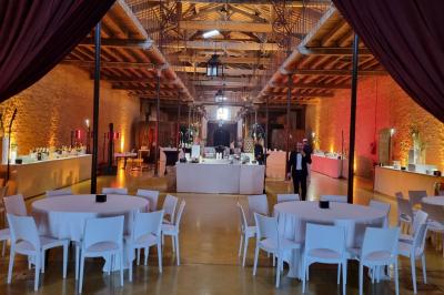 Groupe de personnes rassemblées dans une cour extérieure arborée avec des tables dressées pour un événement.