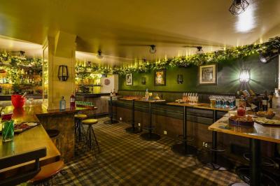 Salle de restaurant avec banquettes vertes, tables en bois garnies de plats variés et seau à champagne au centre.
