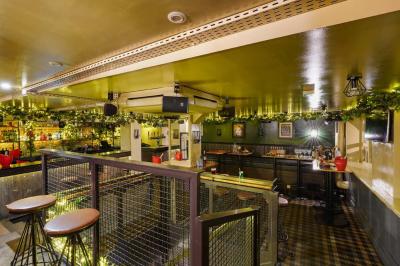 Salle de restaurant avec banquettes vertes, tables en bois garnies de plats variés et seau à champagne au centre.