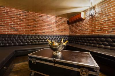 Salle de restaurant avec banquettes vertes, tables en bois garnies de plats variés et seau à champagne au centre.