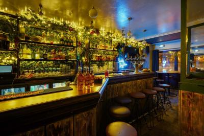 Salle de restaurant avec banquettes vertes, tables en bois garnies de plats variés et seau à champagne au centre.