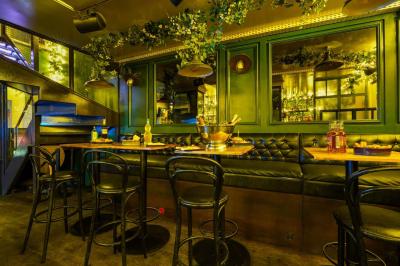 Salle de restaurant avec banquettes vertes, tables en bois garnies de plats variés et seau à champagne au centre.